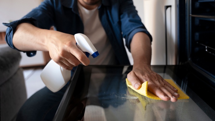 Una persona che pulisce il forno in cucina