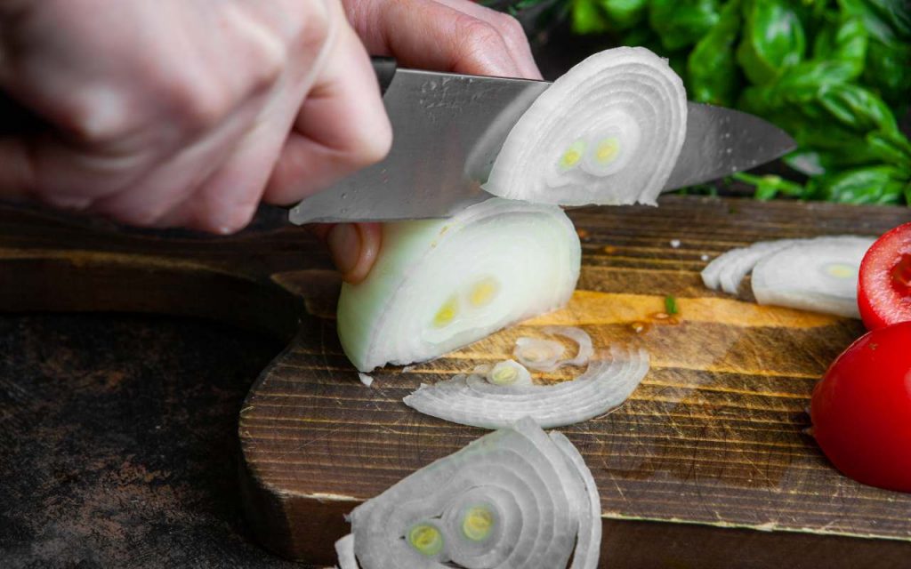 Una persona taglia delle cipolle su un tagliere