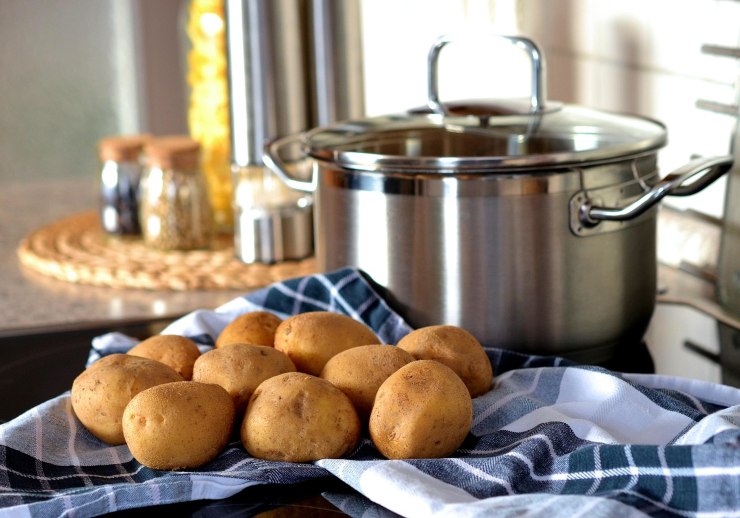 Patate su uno straccio vicino a un pentola sui fornelli