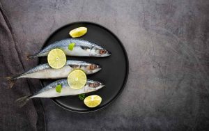 Sardine fresche su un piatto con fette di limone