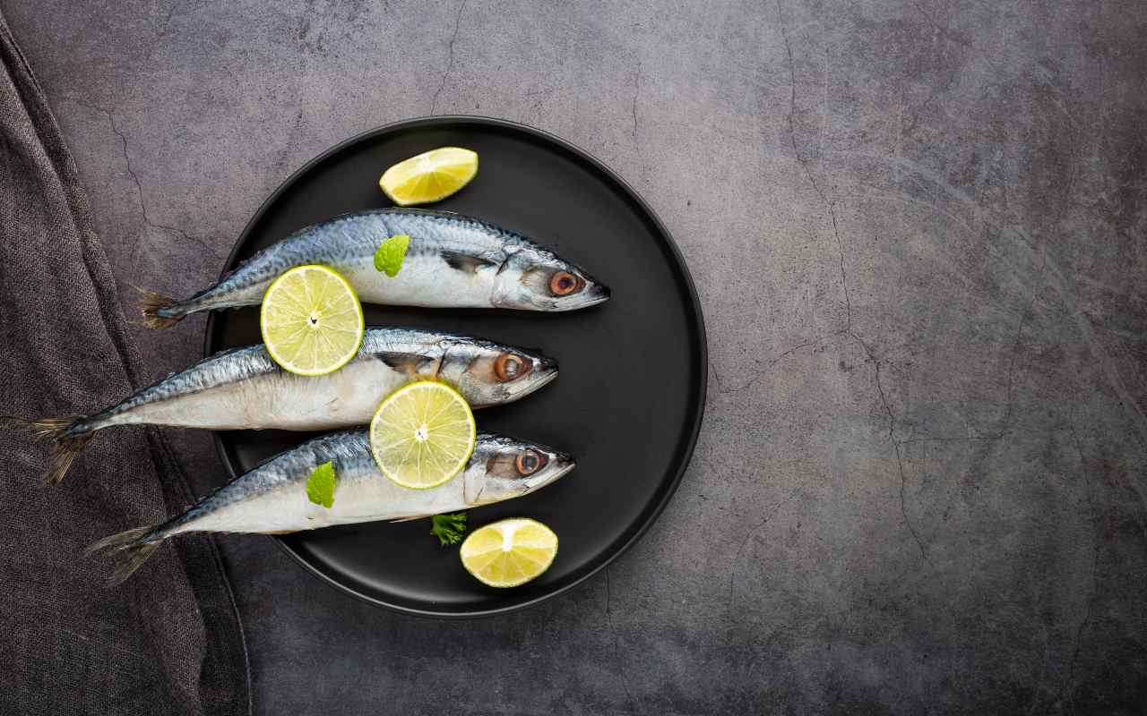 Sardine fresche su un piatto con fette di limone