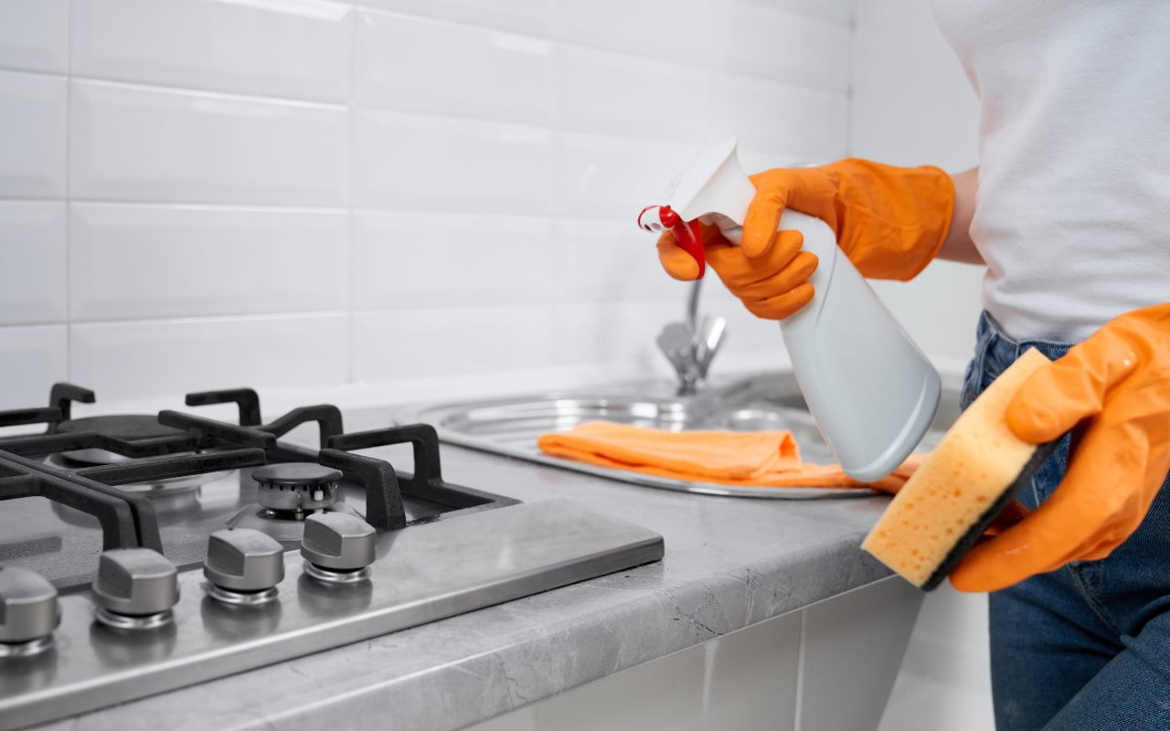 Una persona che pulisce i fornelli in cucina