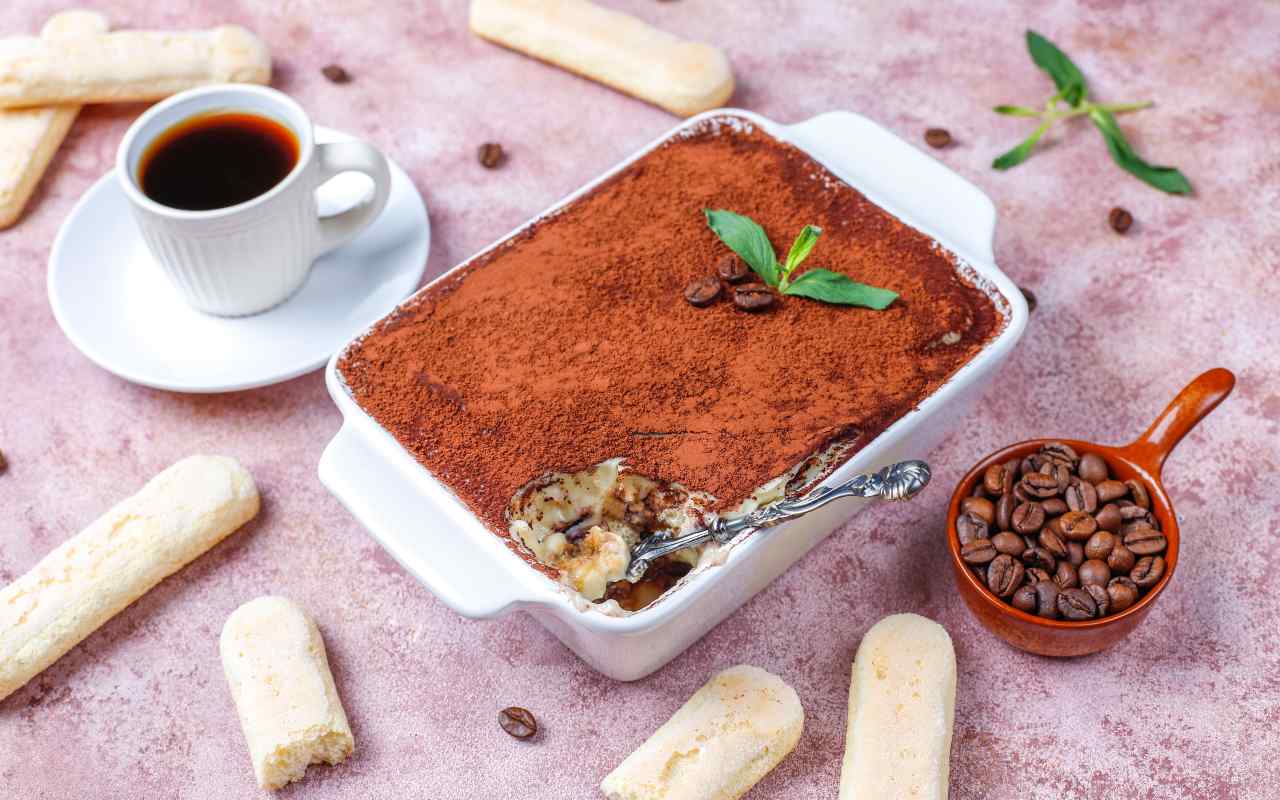 Una teglia di Tiramisù accanto a caffè e savoiardi