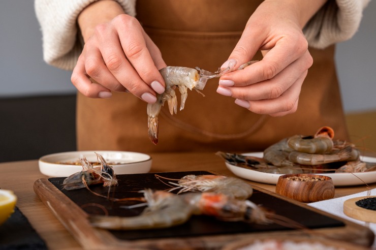 Una persona prepara dei gamberi da cucinare
