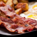 Bacon croccante in un piatto con uova e pane