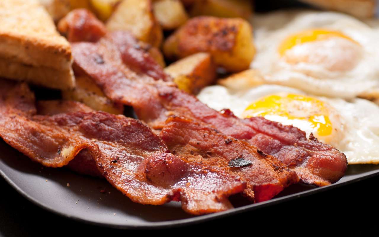Bacon croccante in un piatto con uova e pane