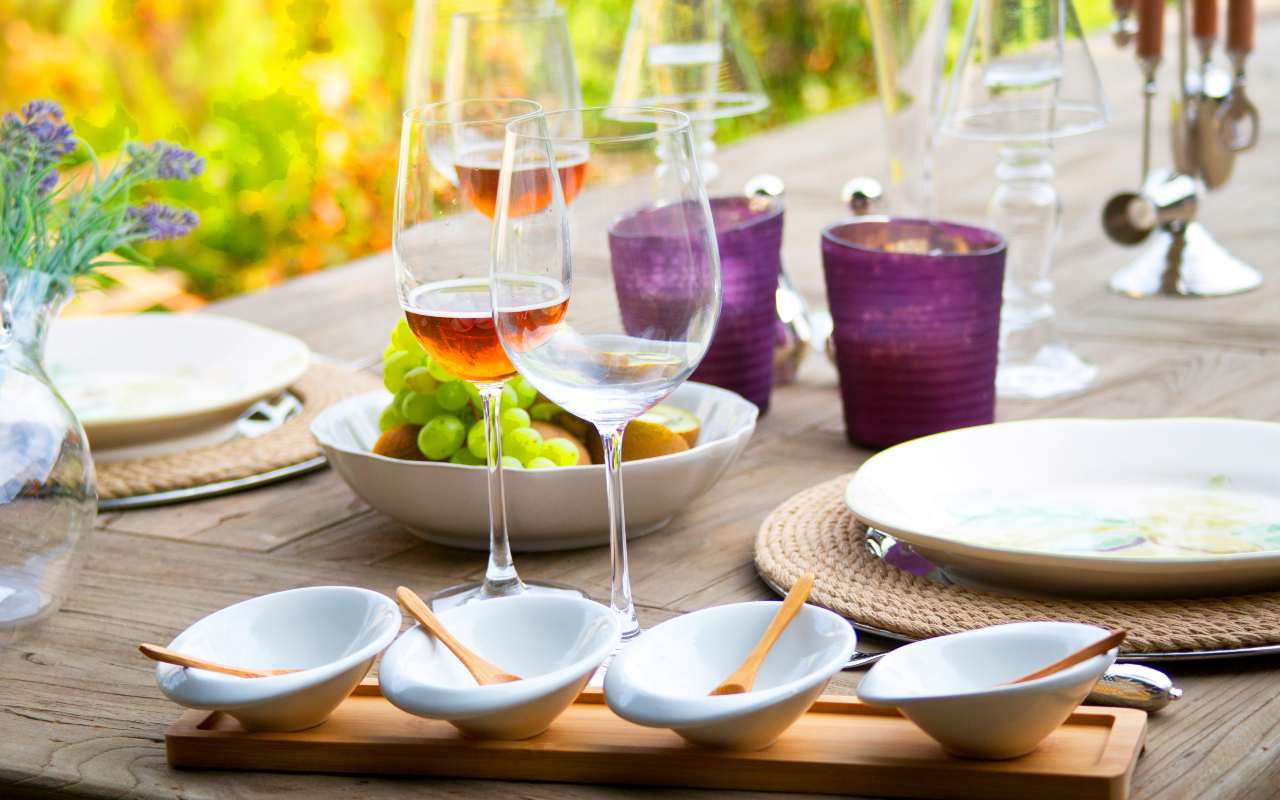 Tavola apparecchiata con bicchieri di vino e piatti