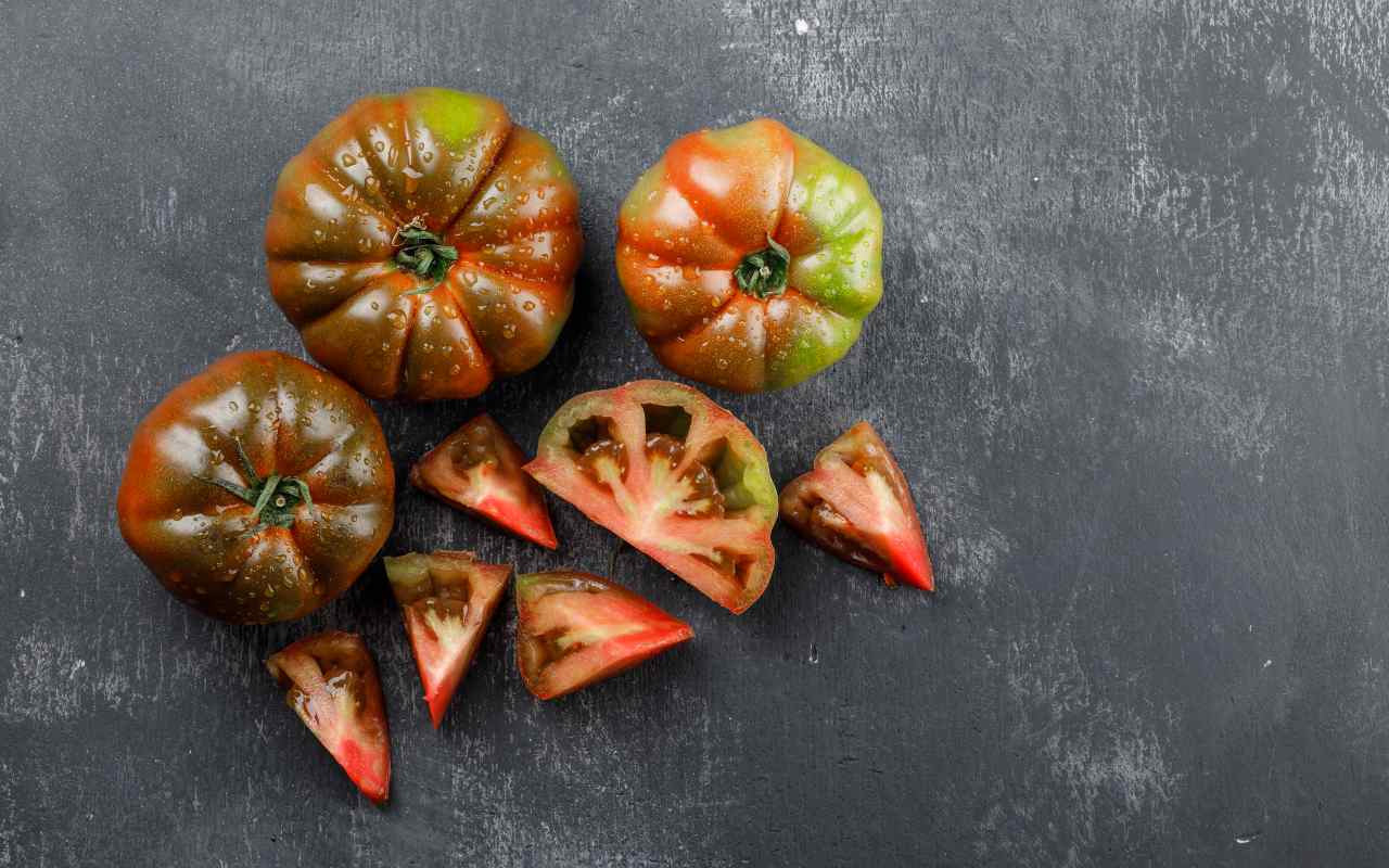 Pomodori cuore di bue interi e a fette su un tavolo